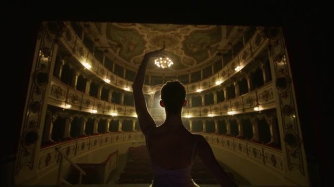 年轻优雅的古典芭蕾舞女舞者穿着白色芭蕾舞短裙的电影镜头将在经典剧院舞台上放映，并在演出开始前进行戏剧