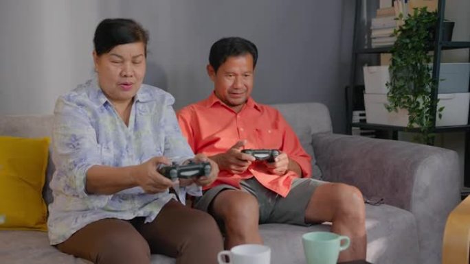 退休亚洲老年人在家客厅玩电子游戏。