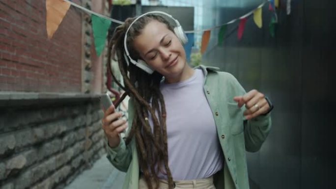 朋克女孩戴着无线耳机在城市街道上跳舞，玩得开心