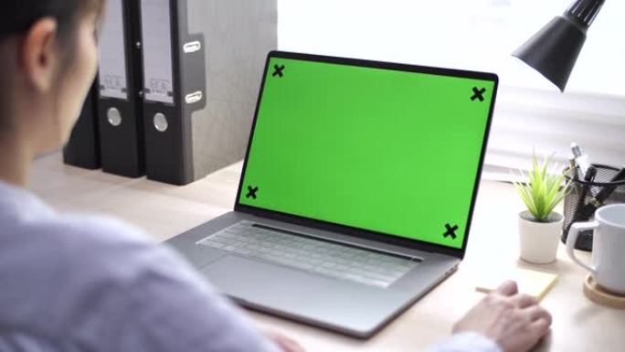 亚洲女性在桌上的笔记本电脑上使用色度键屏幕