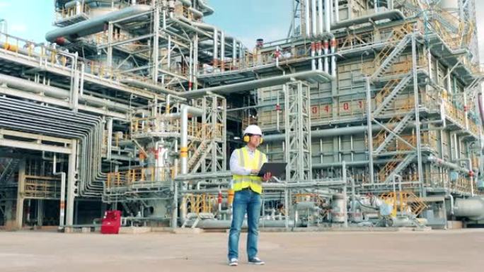 工业工人在炼油厂操作笔记本电脑