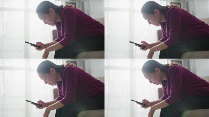 女人的手在家里的客厅使用智能手机，输入消息