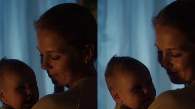 晚上，快乐母亲在舒适的黑暗儿童卧室里抱着可爱的新生婴儿的垂直格式肖像视频。有爱心的妈妈拥抱着新生的小