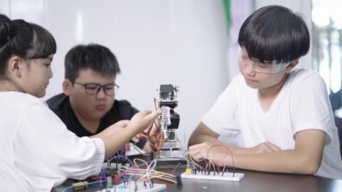一组男孩和女孩的构建和研究机器人STEM编程软件和修复