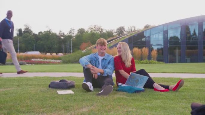 一群大学或大学生坐在校园户外的草地上聊天和工作