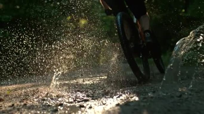 超级SLO MO山地自行车手在一条土路上的水坑中超速行驶