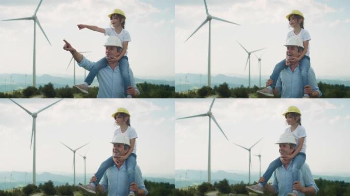 父亲和女儿戴着防护头盔，微笑着指着风电场，背景是风力涡轮机。为子孙后代和我们的孩子提供绿色能源和生态