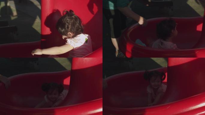 亚洲蹒跚学步2岁的孩子喜欢夏天和她的祖父和祖母在公园的户外操场上玩滑梯