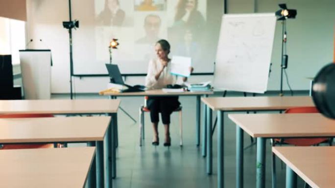 一名正在网上上课的妇女正在空荡荡的教室里被拍摄。在线课堂，远程学习概念。