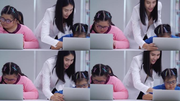 亚裔年轻女教师与唐氏综合症女学生在小学教室教电脑。残疾收集2019