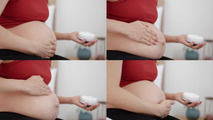 Pregnant woman applying skincare cream on her bell
