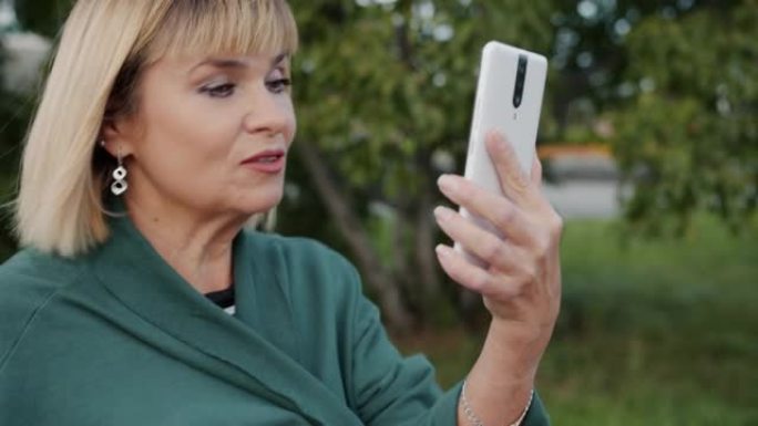 快乐的社交女士在户外使用智能手机进行在线交流的视频通话中聊天