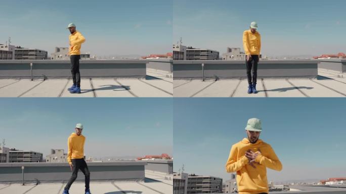 跳舞的人嘻哈舞者穿着黄色连帽衫在城市屋顶上表演自由式舞蹈动作