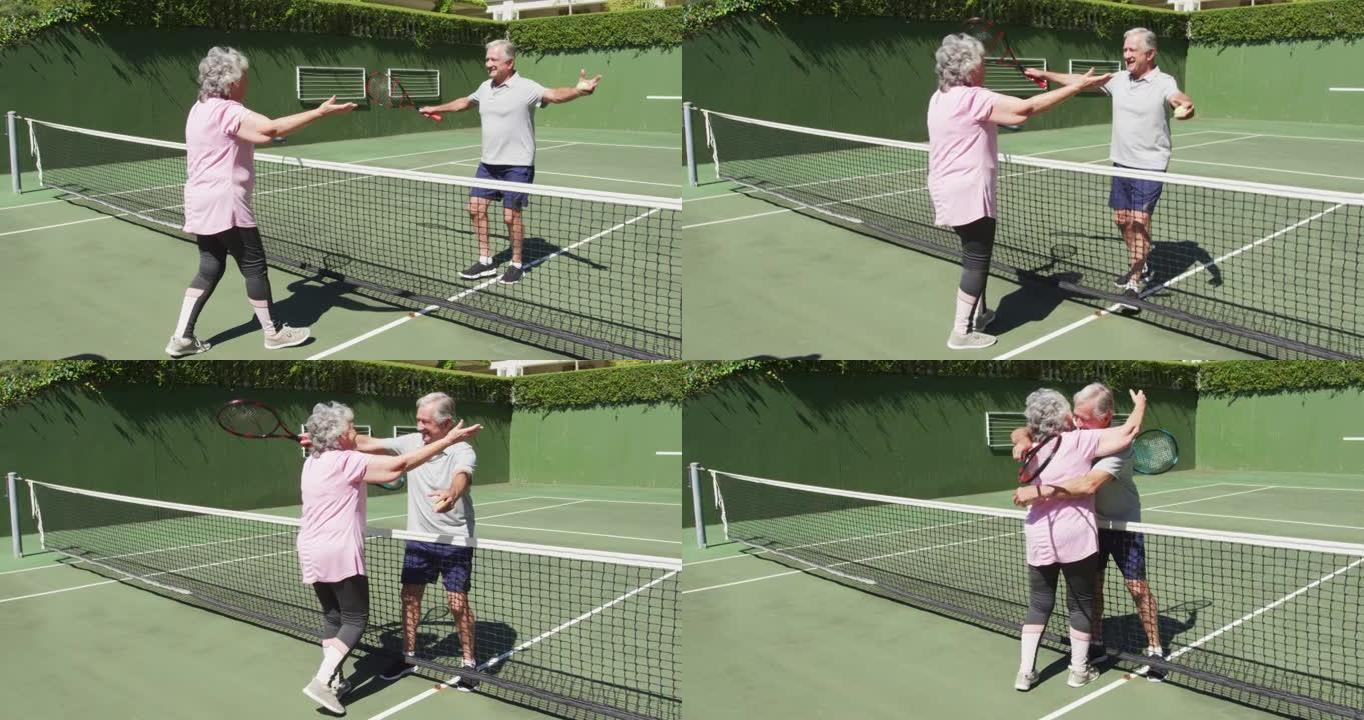 快乐的高加索高级夫妇在玩游戏后在室外网球场拥抱