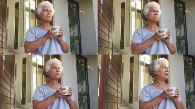 非裔美国高级妇女在家中站在前门时喝咖啡