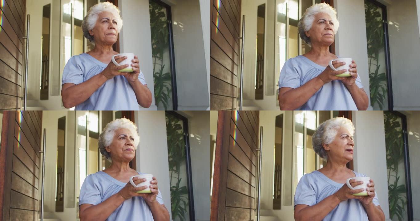 非裔美国高级妇女在家中站在前门时喝咖啡