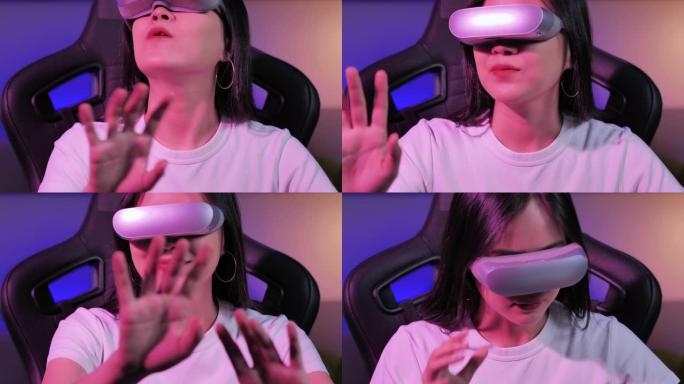 亚洲少女戴着虚拟现实耳机，坐在办公桌前打手势，晚上在彩色紫外线照明客厅中触摸空气。技术