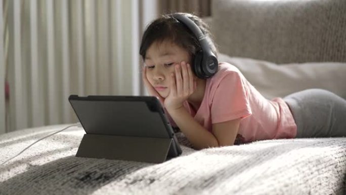 女孩在家客厅沙发上的数字平板电脑在线学习