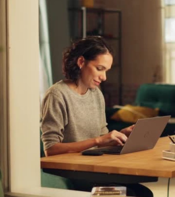 垂直屏幕: 西班牙裔妇女使用笔记本电脑，坐在她公寓的客厅。专业女性远程在线工作，计划，集思广益新项目