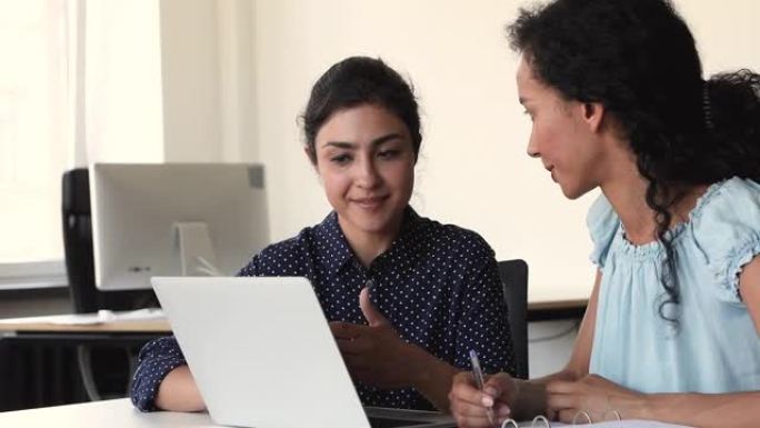 多种族女性同事在项目中使用笔记本电脑一起工作