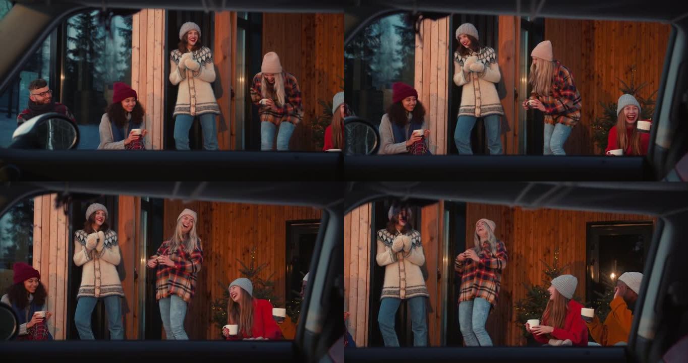 从打开的车窗观看，一群快乐的朋友聊天，在舒适的木制冬季房屋露台享受热饮慢动作
