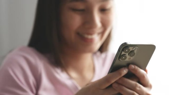 微笑的亚洲年轻女子使用智能手机