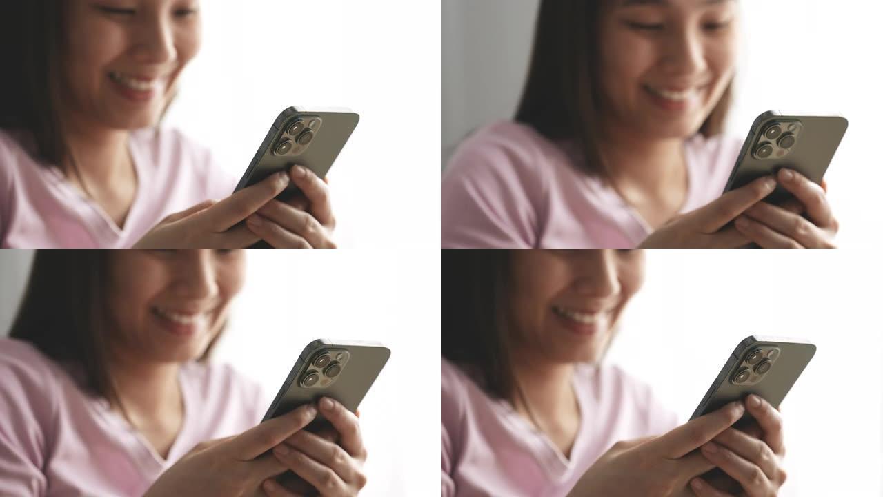 微笑的亚洲年轻女子使用智能手机
