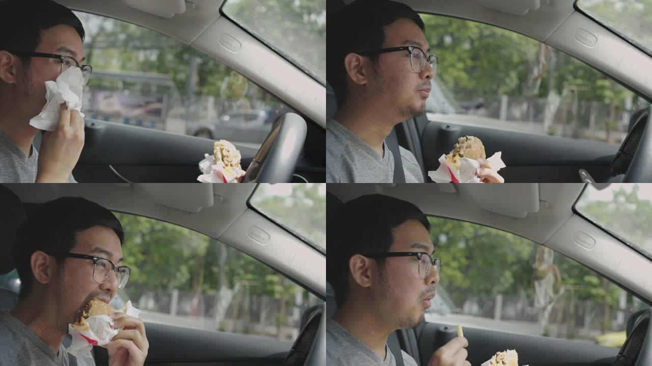 亚洲男子开车时吃汉堡