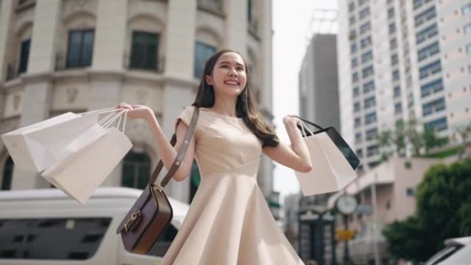 快乐亚洲女人在城市购物后背着购物袋