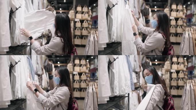 新常态购物，亚洲女子戴口罩在商场服装店购物