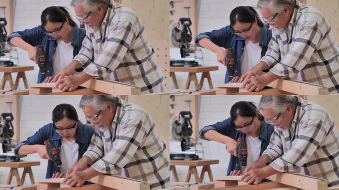 工人木匠，70岁的老人和十几岁的女孩一起在工厂里和司钻一起制作木制家具。工厂和制造概念。