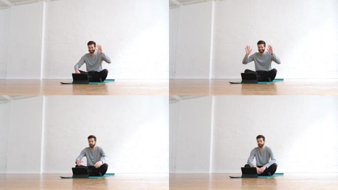 坐在瑜伽垫上的男人在瑜伽课上挥舞着他的数字平板电脑