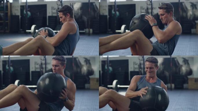 年轻的男性健美运动员在训练健身房进行耐力和肌肉调理的核心力量练习。健身中心用加重的药球做俄罗斯扭曲的