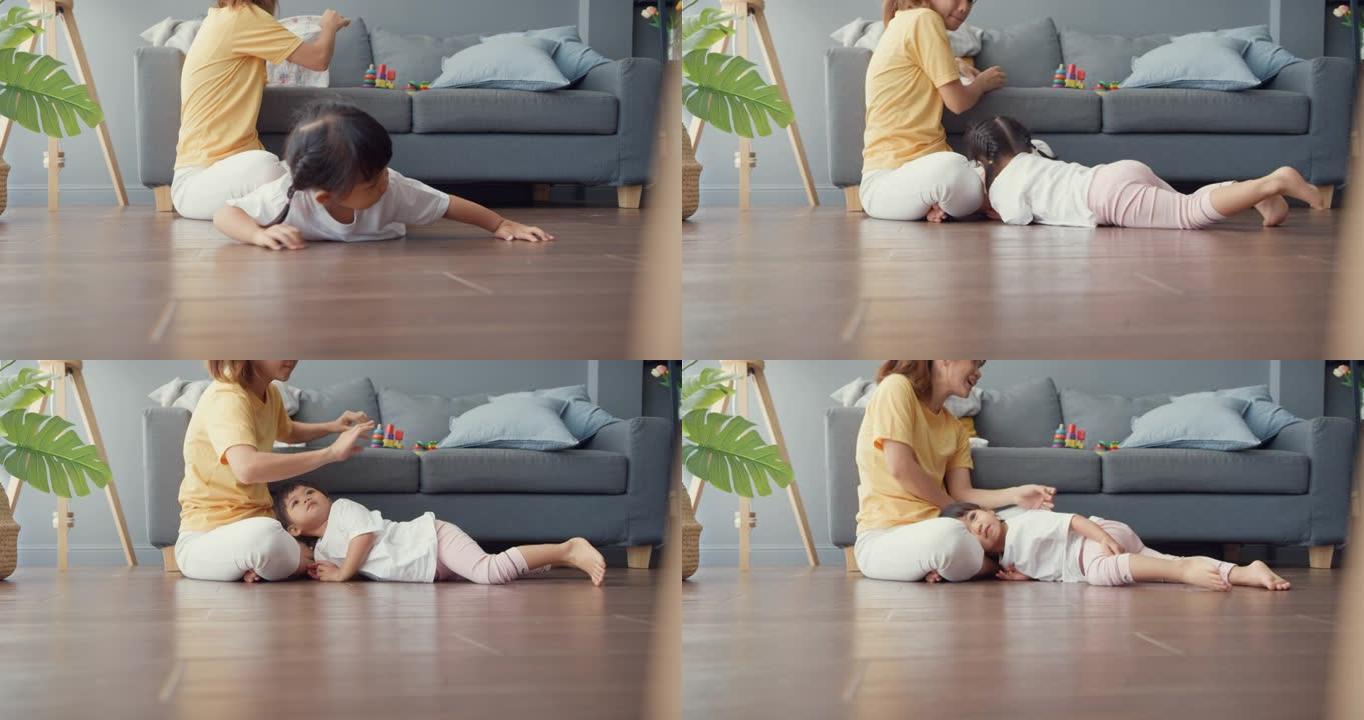 快乐快乐的亚洲家庭妈妈追逐她可爱的烦躁的孩子，她在地板上爬行，在家里的客厅放松。