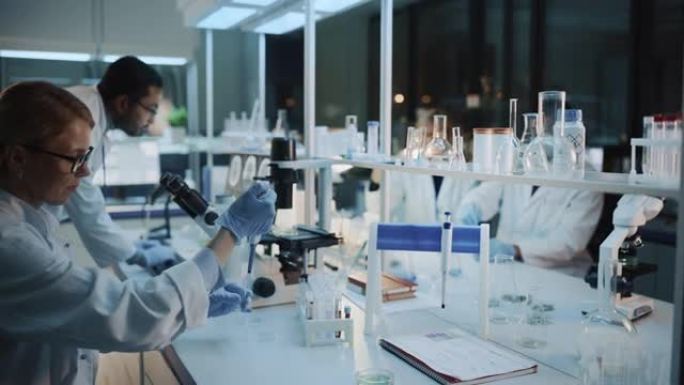 医学研究科学家团队在显微镜，试管，微量移液器和台式计算机的帮助下进行实验。现代生物应用科学实验室，拥