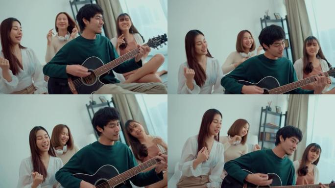 年轻的亚洲男子在一群年轻女子的包围下弹吉他，并在室内举行家庭聚会