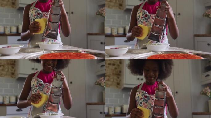 非裔美国女孩在厨房做披萨磨碎奶酪