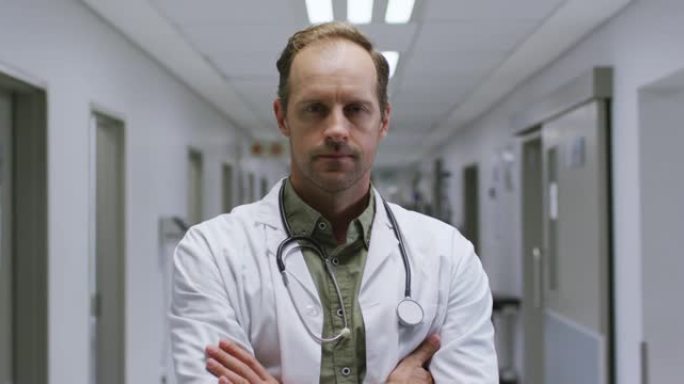 站在医院走廊上双臂交叉的白人男性医生的肖像