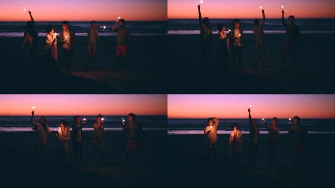 4k视频片段，一群无法识别的朋友一起站在海滩上，晚上玩烟火