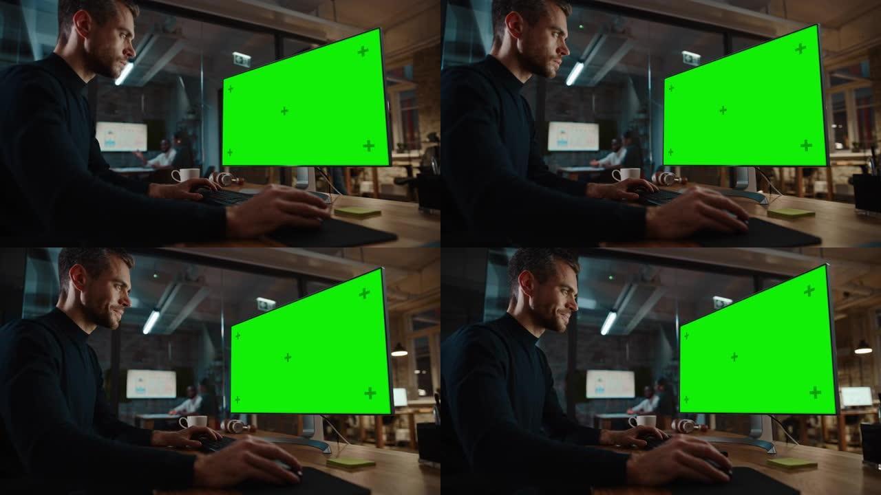 年轻英俊的专家在繁忙的创意办公室与同事一起在台式计算机上使用绿屏模拟显示。修剪胡须的男经理穿着休闲的