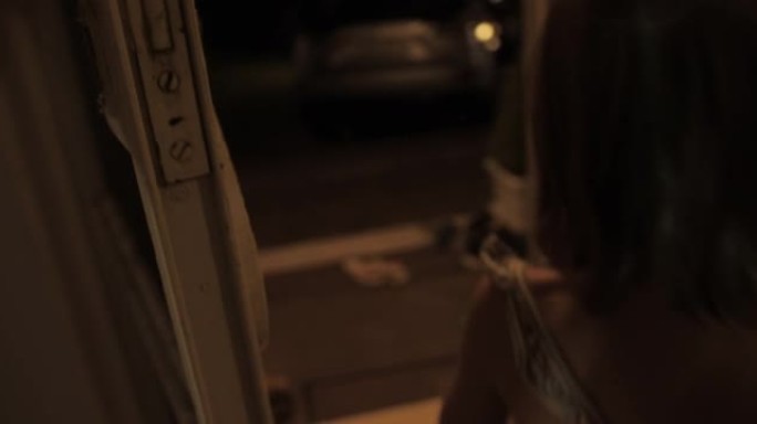 摄像机男子的手在晚上打开老房子的门，带着孩子的年轻妇女在公路旅行前慢动作。