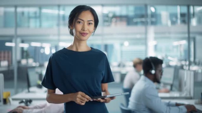 成功的女商人穿着时髦的衣服，使用平板电脑，站在现代多元化的办公室从事金融、商业和营销项目。美丽的亚洲