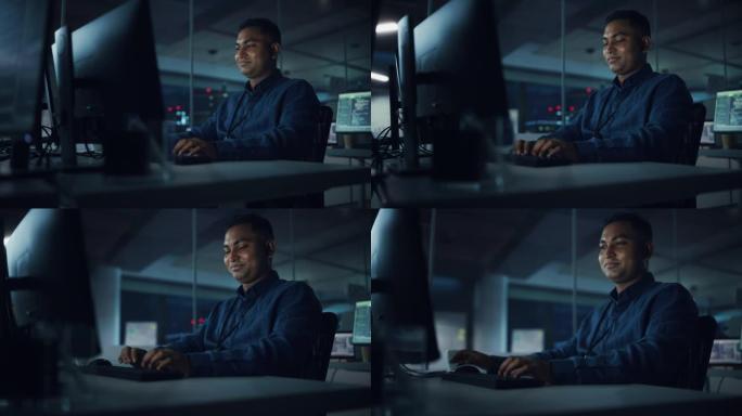 夜间办公室: 在台式电脑上工作的英俊印度男子的肖像。数字企业家打字，创建现代软件，电子商务应用程序设