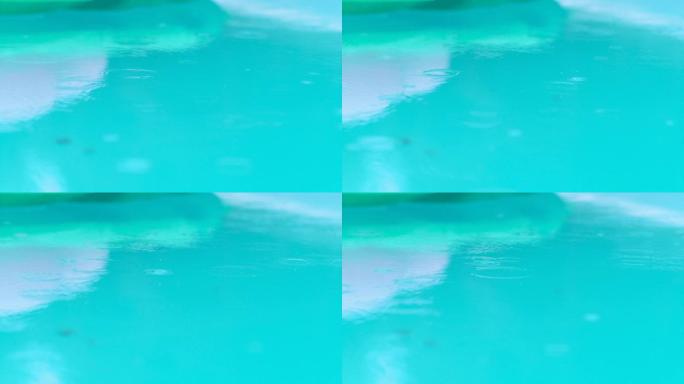 特写: 秋雨在家庭游泳池的表面上创造同心圆。