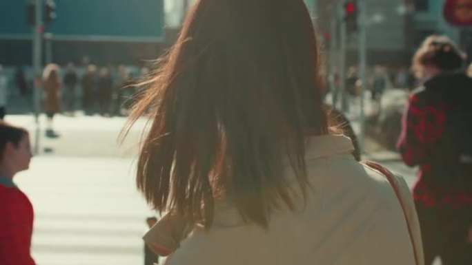 在风城街道慢动作中，美丽体贴的年轻女子穿着秋衣触摸棕色头发的电影镜头。