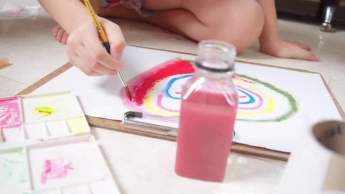 亚洲小女孩在家时在客厅绘画和绘画她的艺术和工艺。她喜欢用水彩和画笔在白纸上创作艺术作品，并从中获得乐