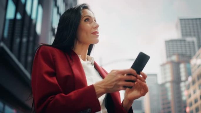 在大城市的街道上使用智能手机的多种族成年女商人的肖像。自信的经理在去办公室的路上与网上的人联系，发信