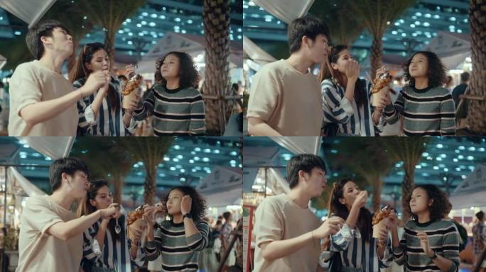 年轻的亚洲朋友在夜市享受街头美食。