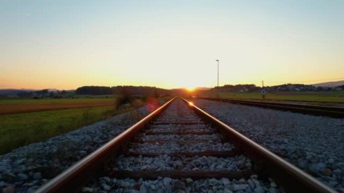 低角度: 在金色秋天的灯光下沿着橙色发光的铁轨运动