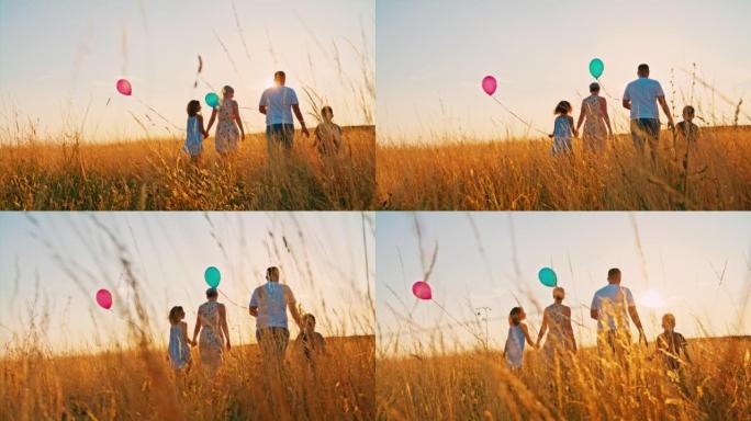 有两个孩子的SLO MO家庭在黄金时段在高高的羊茅草中行走时拿着气球